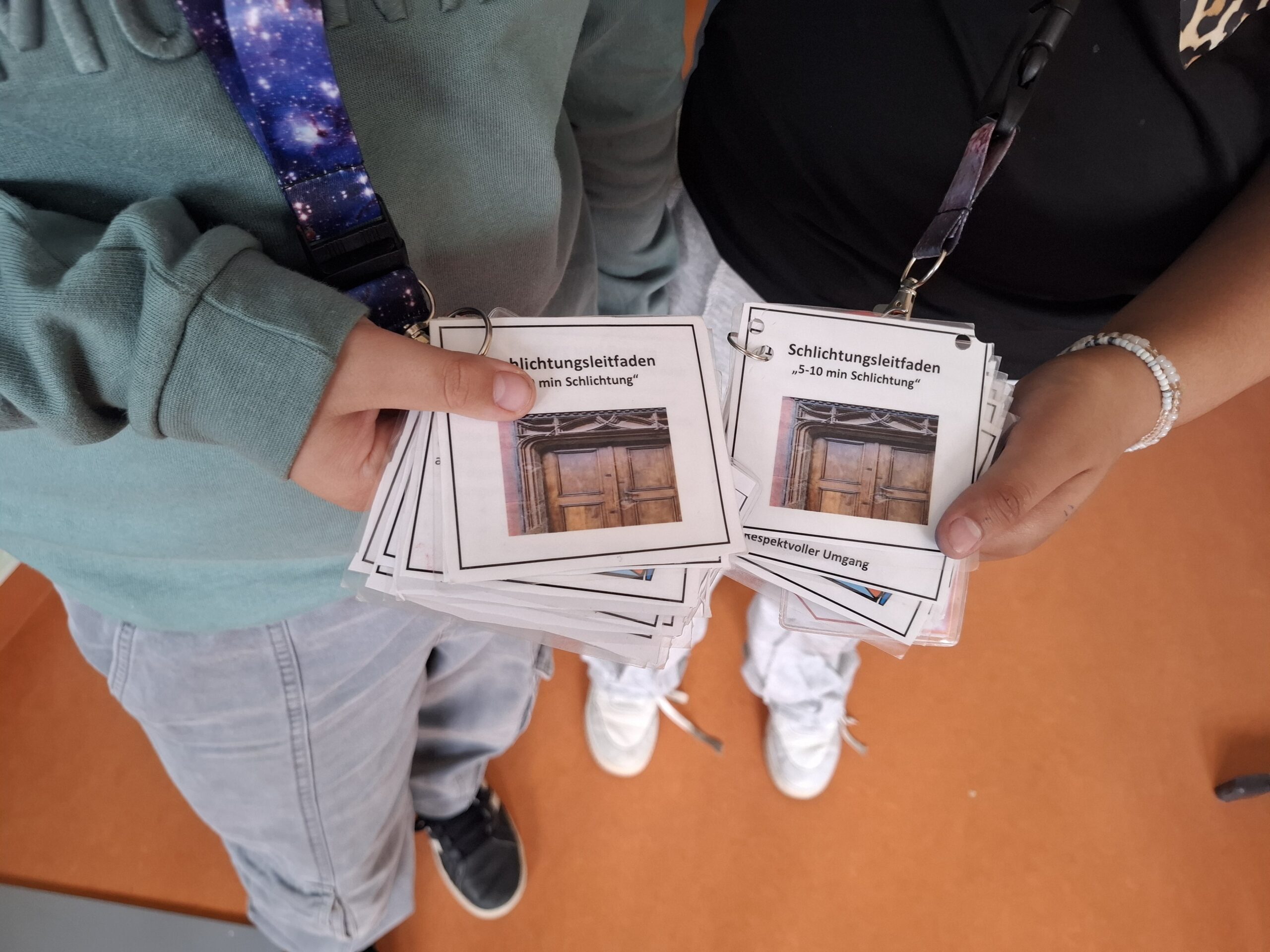 Jugendliche halten Broschüren in den Händen - Projekt Streitschlichter*innen