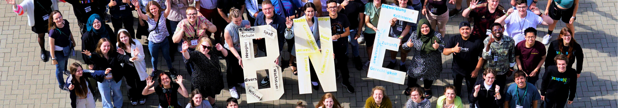 Gruppenbild von vielen Personen. Sie halten drei große Buchstaben aus Holz: BNE
