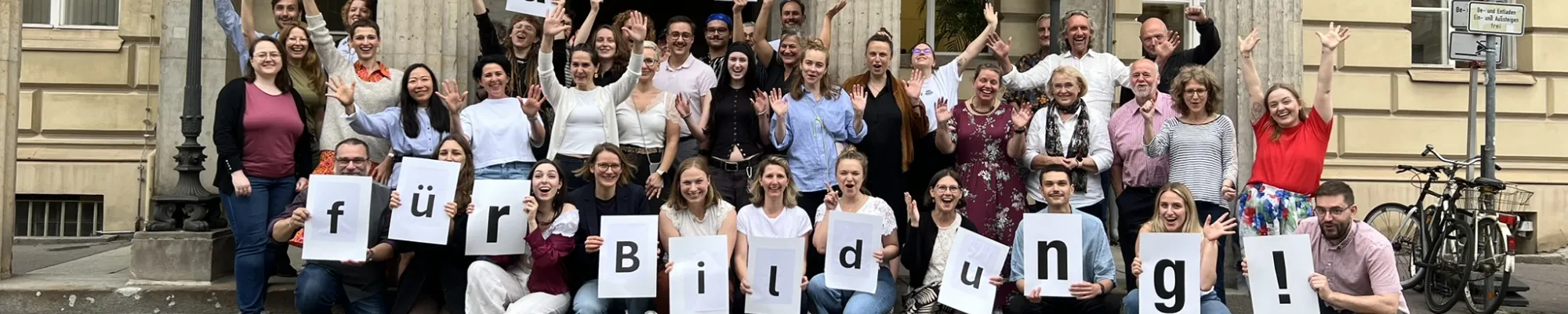 Mitarbeiter*innen der Stiftung Bildung halten vor dem Palais am Festungsgraben Buchstaben in die Höhe mit "Alle für Bildung" - Jahresrückblick 2024 Slide