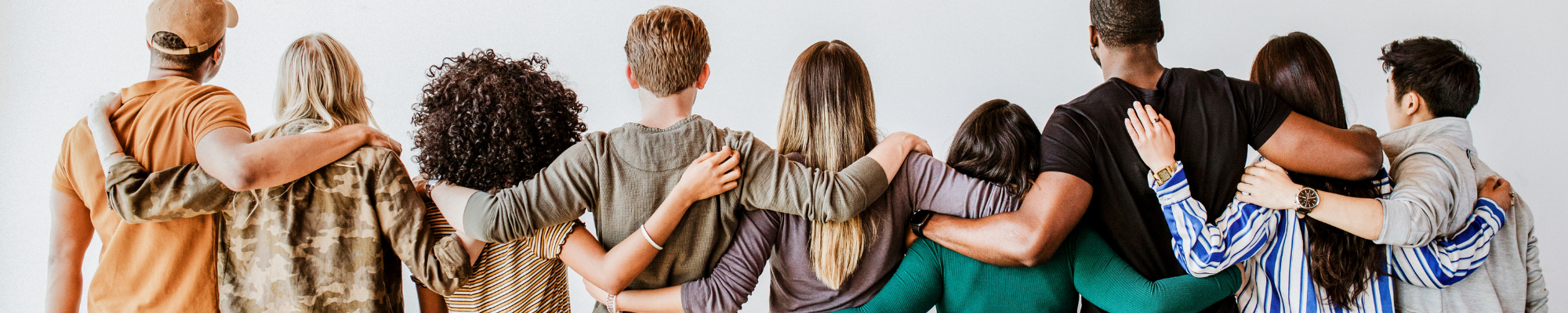 mehrere Menschen von hinten, sie stehen nebeneinander und haben die Arme umeinander gelegt